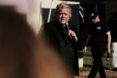 Stephen K. Bannon wears dark-colored clothing while holding a microphone.