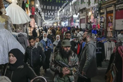 FILE - An armed opposition fighter walks among costumers at the Al-Hamidiyeh market inside the old walled city of Damascus, Syria, Tuesday, Dec. 10, 2024. 