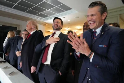 President Donald J. Trump with Vice President-elect JD Vance and Pete Hegseth, standing in a row dressed in suits and ties. Mr. Vance and Mr. Hegseth are laughing.