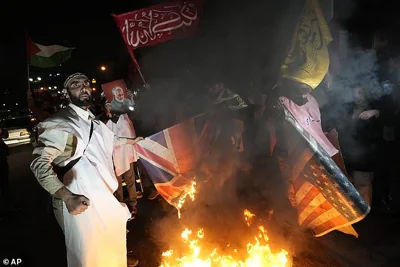 Iranian demonstrators burn representations of British and U.S. flags during a protest against the US and British military strike against Iranian-backed Houthis in Yemen, in front of the British Embassy in Tehran, Iran, Jan. 12, 2024