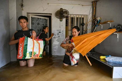 DELUGED DWELLING Residents, carrying their belongings, leave their house that is partially submerged in floodwaters in Vietnam’s capital Hanoi on Sept. 11, 2024, days after Typhoon Yagi hit the country’s north. AFP PHOTO