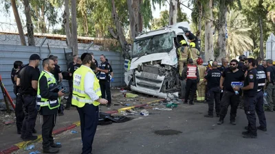 Israeli police and rescue workers climb on a truck to inspect the body of a driver that rammed into a bus stop near the headquarters of Israel's Mossad spy agency.