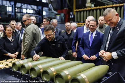 Zelensky smiles as he signs a 155mm artillery shell which likely could be destined for the battlefields in his country where hundreds of thousands of life-altering and life-ending casualties have occurred. Shapiro (3R) and Casey (4R) can be seen in blue suits