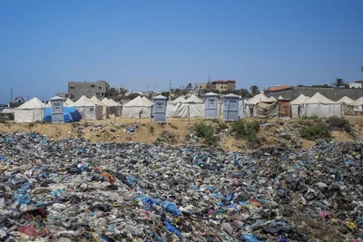 Garbage piles up next to a makeshift tent camp for Palestinians displaced by Israel's air and ground offensive in Nuseirat refugee camp.