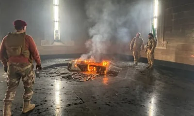 Rebel fighters stand next to the burning gravesite of Syria’s late president Hafez al-Assad at his mausoleum in the family’s ancestral village of Qardaha