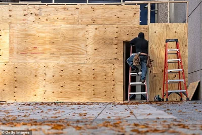 Workers are seen boarding up ground level storefronts and buildings along Pennsylvania Avenue near the White House