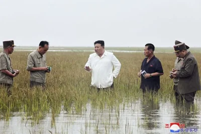 Kim Jong Un with officials in flooded field