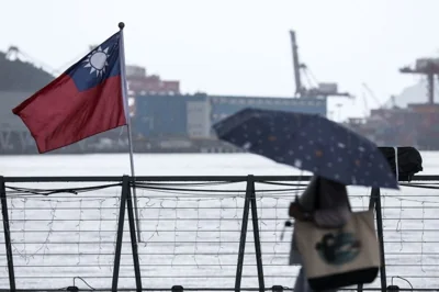 A woman walks past a Taiwanese national flag at Maritime Plaza in Keelung on October 22, 2024. - China's military began a live fire exercise near Taiwan, maintaining pressure on the self-ruled island after staging large-scale drills and President Xi Jinping called for troops to prepare for war. (Photo by I-Hwa CHENG / AFP)