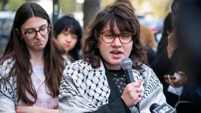 Soph Askanase speaks into a microphone during a protest