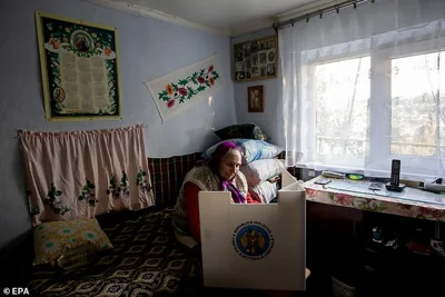 An elderly woman casts her vote into a mobile ballot box in Hrusevo village, Moldova