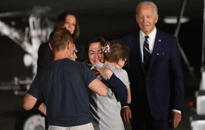 US President Joe Biden and Vice President Kamala Harris watch as former prisoner held by Russia US-Russian journalist Alsu Kurmasheva embraces her family as she arrives at Joint Base Andrews in Maryland on 1 August 2024