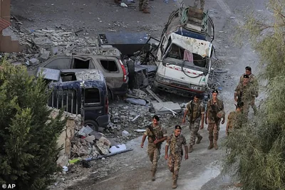 Lebanese army soldiers walk by destroyed cars at the site where an Israeli airstrike hit a building on October 12