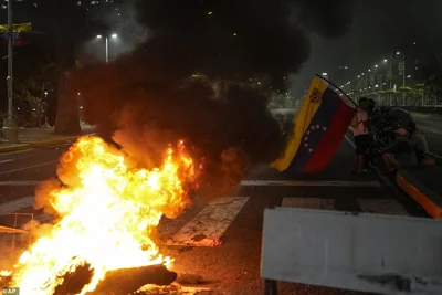 A man holds a Venezuelan flag near a barricade on Bolivar Avenue in Caracas, Venezuela