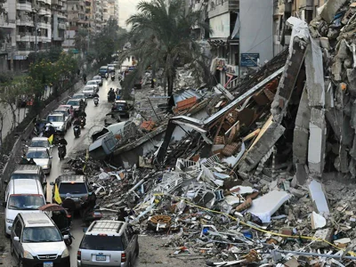 Motorists drive past a destroyed building in Beirut’s southern suburbs