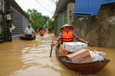  A woman rows a boat along a flooded street carrying packages of food in Thai Nguyen province, Vietnam, Sept. 10. AFP-Yonhap