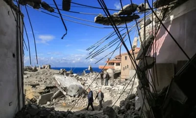 People walk through the rubble of destroyed buildings