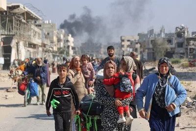 Palestinians displaced from shelters in Beit Hanoun cross the main Salaheddine road into Jabalia in the northern Gaza Strip