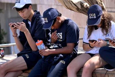 Students look at their phones in Melbourne on November 28, 2024 as Australia looks to ban children under 16 from social media with claims social media platforms have been tarnished by cyberbullying, the spread of illegal content, and election-meddling claims. - Australia is among the vanguard of nations trying to clean up social media, and the age limit legislation will make it among the world's strictest measures aimed at children. (Photo by William WEST / AFP)