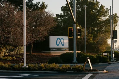 A sign displaying the Meta logo near a street intersection.