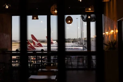 Three parked jets can be seen through windows in an airport.