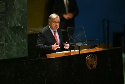 Antonio Guterres speaking from a lectern bearing the U.N. logo.