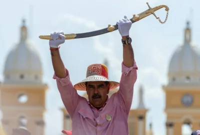 Nicolas Maduro in a straw hat lifts up a sword with white-gloved hands.