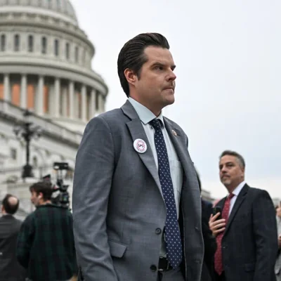 Matt Gaetz in a gray suit and blue tie in front of the U.S. Capitol building.