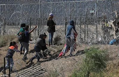 Migrants wait between barbed wire near the US border wall, in Ciudad Juarez, Chihuahua, Mexico, 26 May 2024