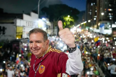 Edmundo Gonzalez flashes a thumbs-up as he stands above crowds gathered for a rally.