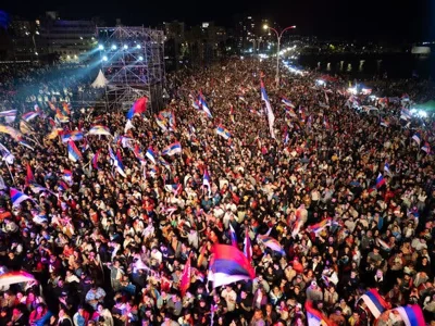 A crowd at night, with many flags being waved.