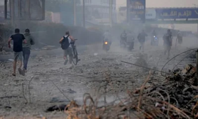 People run from a warplane sound amid the debris of destroyed buildings hit by Israeli airstrikes in Dahiyeh, southern Beirut, on Sunday