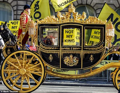 Charles III and Queen Camilla pass a group of anti-Royalists with 'Not my King' placards during the state opening of Parliament