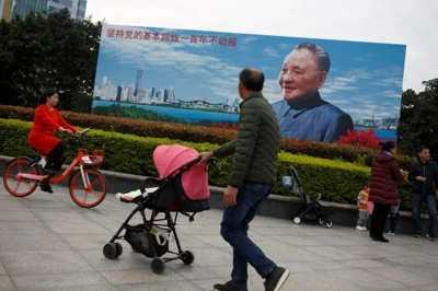 People walk past a poster of late Chinese leader Deng Xiaoping, who launched the country on its "Reform and Opening" program, in Shenzhen, Guangdong Province, China, December 13, 2018. Picture taken December 13, 2018. REUTERS/Thomas Peter