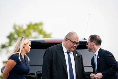 Steven Cheung, center, talking to a man while a woman with blond hair stands behind him. 