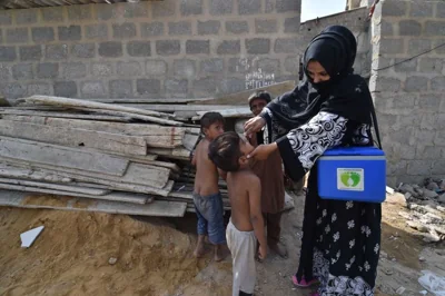 Health workers mark locations as they administer polio vaccines to children during a door-to-door vaccination campaign in Karachi