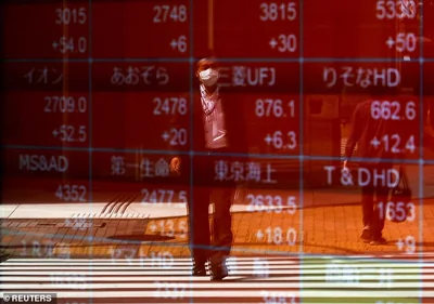 A man is reflected on an electric stock quotation board outside a brokerage in Tokyo