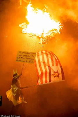 A protester in Tel Aviv dressed as the Statue of Liberty calls out US President Joe Biden for a hostage deal as thousands of Israelis stage a demonstration by blocking roads and lighting fires as they demand ceasefire and a hostage deal