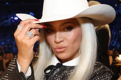 Beyoncé holds the brim of a white cowboy hat.