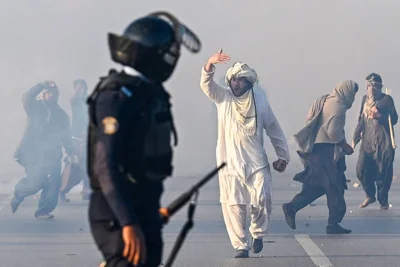 HAZY SITUATION A supporter of the Pakistan Tehreek-e-Insaf party walks toward a member of security forces after tear gas was fired to disperse a crowd of protesters demanding the release of former prime minister Imran Khan in Pakistan’s capital Islamabad on Nov. 26, 2024. AFP PHOTO