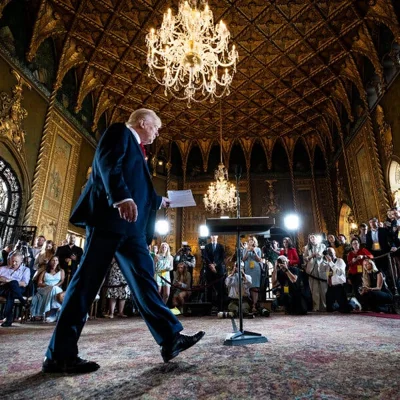 Donald Trump approaches a microphone in front of a scrum of reporters.