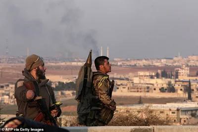 An injured fighter holds a position with a fellow militant on the outskirts of the northern city of Aleppo on November 29