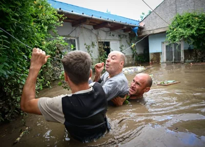 Local residents rescue an elderly man (center) from the rising flood waters in the Romanian village of Slobozia Conachi on September 14 2024. AFP PHOTO