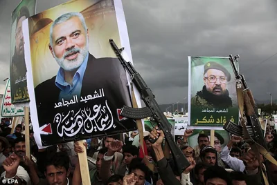 Houthi supporters hold placards with pictures of Ismail Haniyeh (L) and Hezbollah senior commander Fuad Shukr (R) during a protest following their deaths, in Sana'a, on August 2