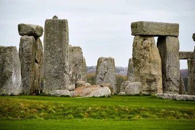 A view from some ways away looking at the inner ring of Stonehenge monoliths on an overcast day.