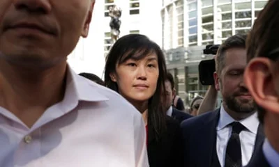 Linda Sun is surrounded by men in suits and dress shirts as she exits a Brooklyn federal court