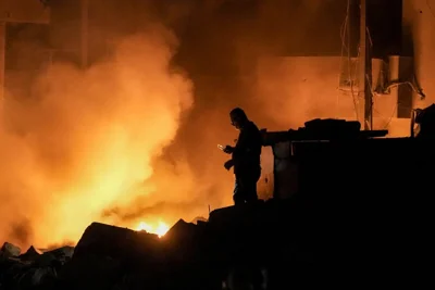 A man uses his mobile phone as flames and smoke rise at the scene of buildings hit by an Israeli airstrike in central Beirut, 10 October, 2024