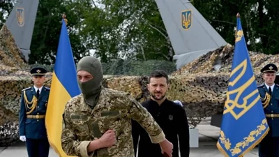 TOPSHOT - Ukraine's President Volodymyr Zelensky (C/R) stands in front of a pair of F16 fighter jets after giving an award to a Ukranian fighter pilot during Ukrainian Air Forces Day at an undisclosed location on August 4, 2024. (Photo by Sergei SUPINSKY / AFP)