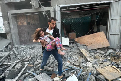 A Palestinian man carries away an injured child from a home that was hit in an Israeli strike on the Jabalia refugee camp Photo by -/AFP via Getty Images)