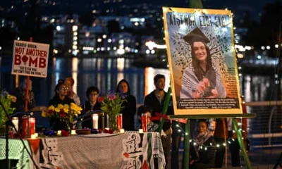 people next to lake with poster of Ayşenur Ezgi Eygi