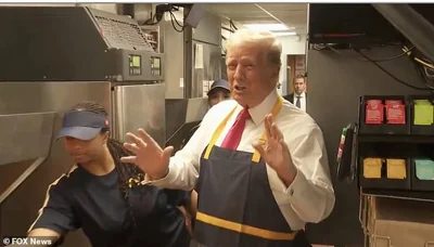 Former President Donald Trump grins as he chats with employees at a suburban Philadelphia McDonald's on Sunday. Trump was taught how to make McDonald's trademark French fries, in a move designed to troll Vice President Kamala Harris